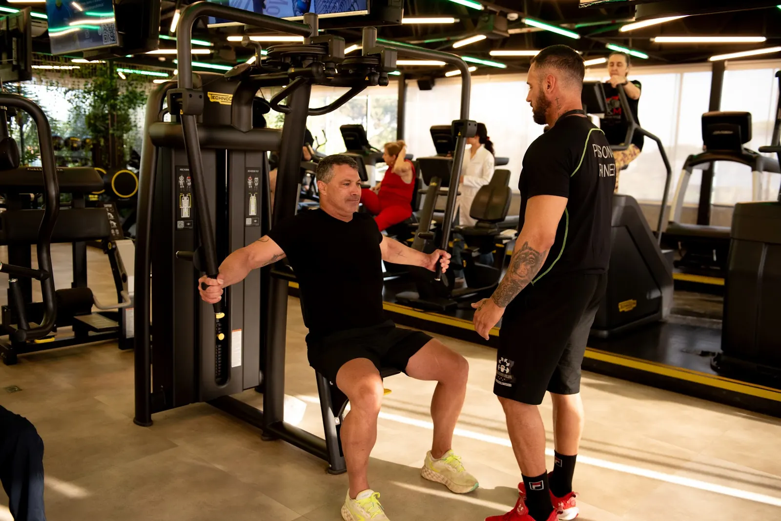 Personal trainer orientando aluno em equipamento de musculação