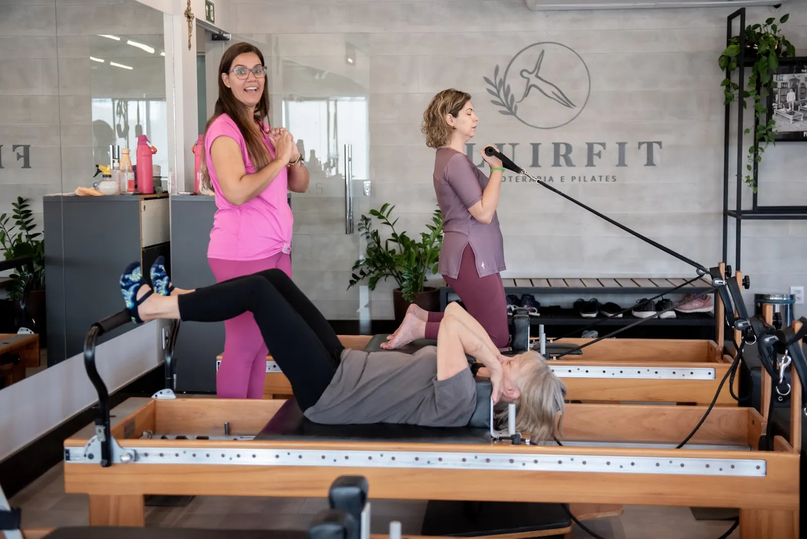 Aula de Pilates em reformer com acompanhamento de duas profissionais